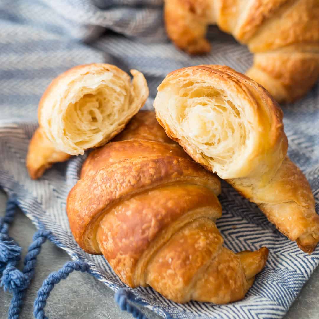 Croissants playfully scattered on a blue linen cloth