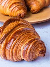 Glossy croissants placed on wooden tray