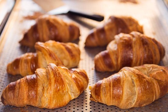 Rows of croissants cooling on a metal tray