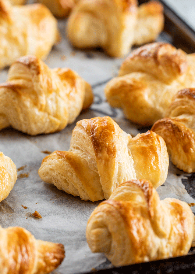 Fresh golden brown croissants on a baking tray